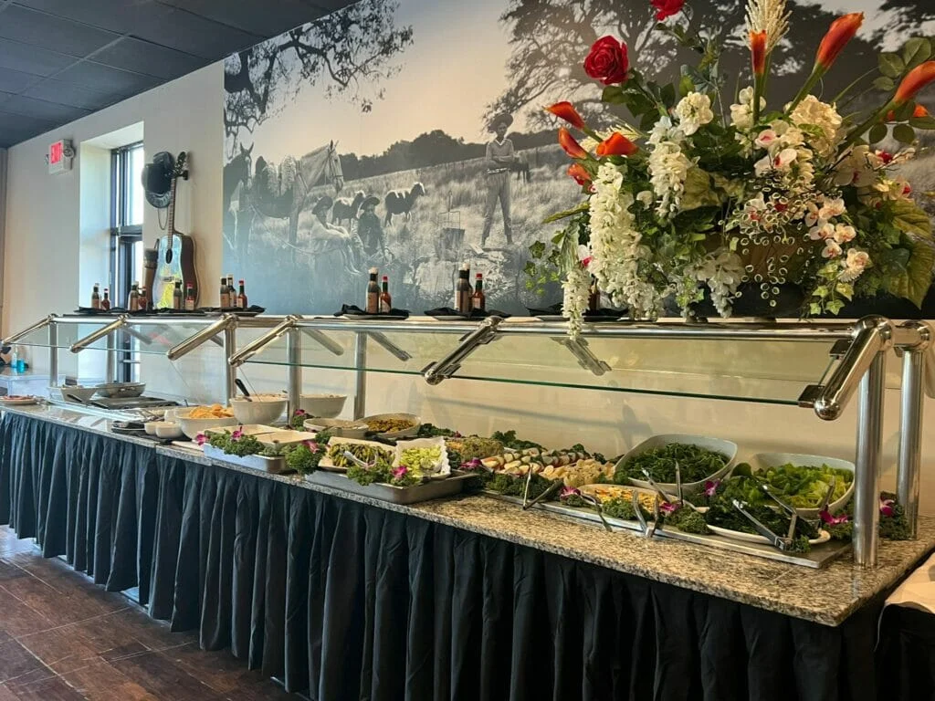 A Churrascaria buffet is set up in a room with a picture of a cowboy.