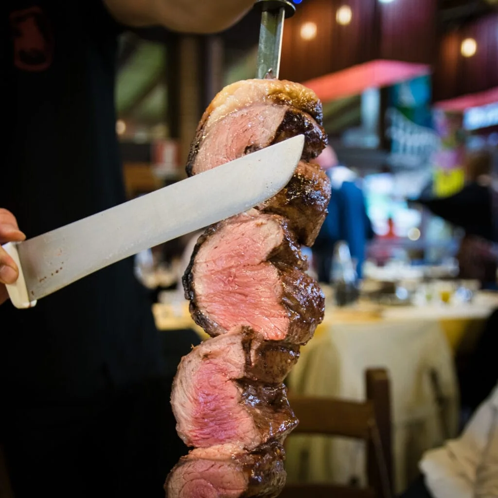 A person holding a knife at a Brazilian Steakhouse.
